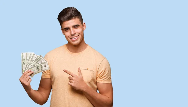 Junger Mann Hält Lächelnd Dollars Der Hand Und Zeigt Zur — Stockfoto