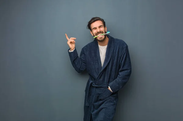 Het dragen van pyjama houden een teethbrush jongeman — Stockfoto