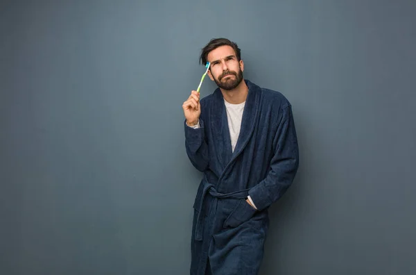 Het dragen van pyjama houden een teethbrush jongeman — Stockfoto