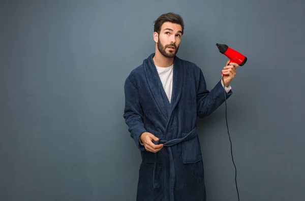Ung man klädd i pyjamas håller en frisör — Stockfoto