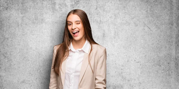 Young caucasian business woman winking, funny, friendly and carefree gesture