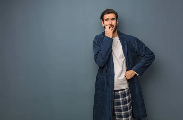 Man wearing pajama biting nails, nervous and very anxious