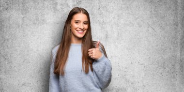 Genç beyaz kadın gülümsüyor ve başparmağını kaldırıyor.