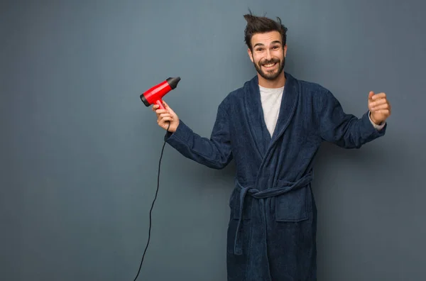 Ung man klädd i pyjamas håller en frisör — Stockfoto