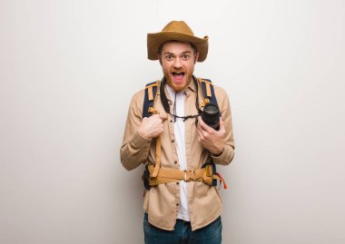 Young redhead explorer man surprised, feels successful and prosperous. Holding a camera. clipart