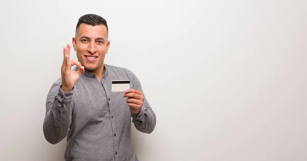 Jovem Latino Segurando Cartão Crédito Alegre Confiante Fazendo Gesto — Fotografia de Stock