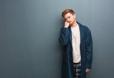 Genç Redhead adam içinde pijama düşünme bir şey, seyir için The yan