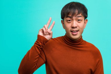 Genç Çinli adam eğlenceli ve mutlu zafer bir jest yapıyor