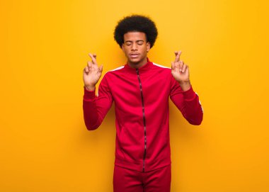 Genç spor siyah adam üzerinde bir turuncu duvar geçiş parmaklar için sahip şans