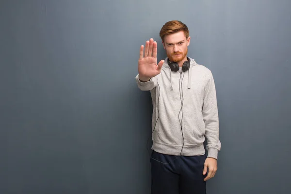 Young fitness redhead man putting hand in front