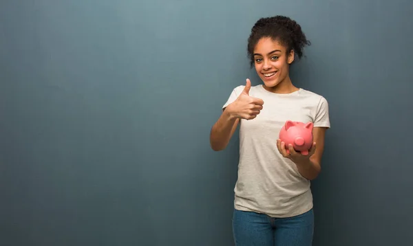 Jovem Negra Sorrindo Levantando Polegar Ela Está Segurando Banco Porquinho — Fotografia de Stock