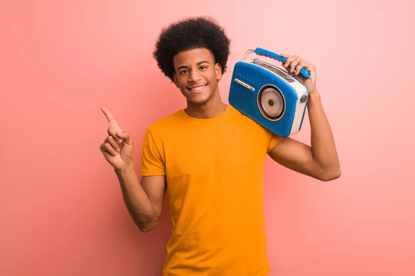 年轻的非洲裔美国人拿着一个老式的收音机指着一边用手指 — 图库照片