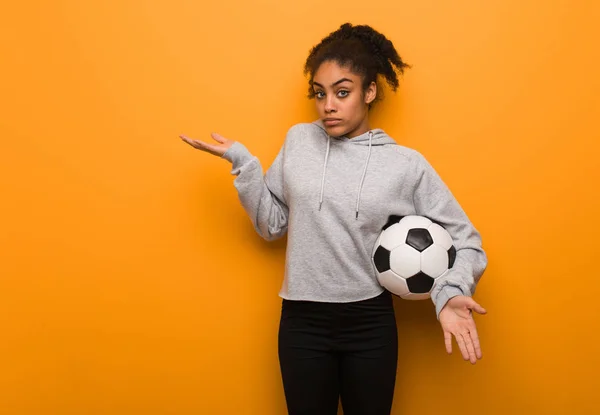 若いフィットネス黒人女性が混乱し 疑わしい サッカーボールを持っている — ストック写真