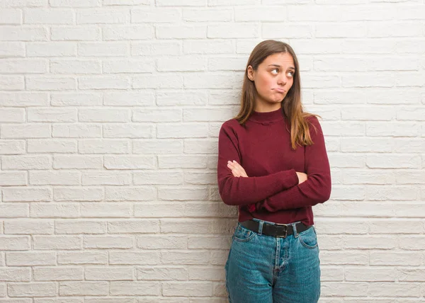 Young cool woman over a bricks wall thinking about an idea