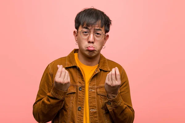 Young chinese man wearing a jacket doing a gesture of need