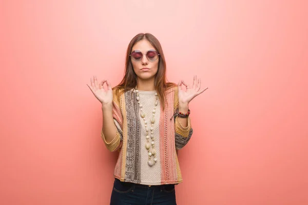 Young hippie woman on pink background performing yoga