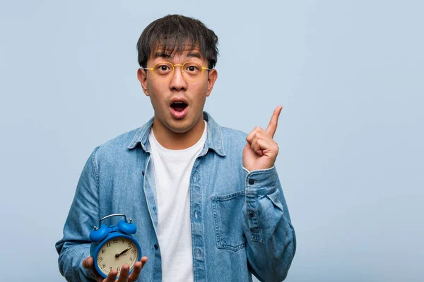 Joven Hombre Chino Sosteniendo Despertador Que Tiene Una Gran Idea —  Fotos de Stock