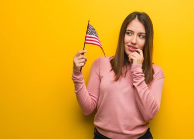 Bir kopya alanı bakarak bir şey hakkında bir Birleşik Devletler bayrağı rahat düşünme tutan genç Sevimli Kadın