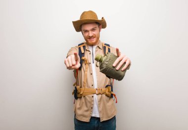 Genç Redhead Explorer adam neşeli ve ön işaret gülümseyen. Bir kantin tutuyor..