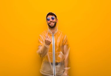 Genç adam gelmek için davet yağmur ceket giyiyor