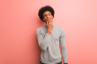 Pembe bir duvar üzerinde genç Afrikalı Amerikalı adam şüphe ve karıştı