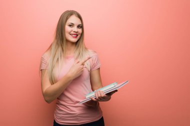 Genç güzel Rus kız parmak ile yan işaret. Kitap tutuyor..