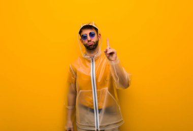 Bir numara gösteren bir yağmur ceket giyen genç adam