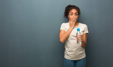 Genç siyah kadın çok korkuyor ve gizli korkuyor. O bir su şişesi tutuyor.