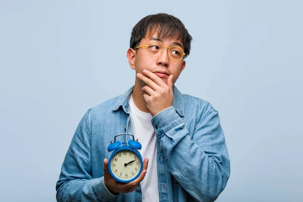 Ung Kinesisk Man Som Innehar Väckar Klocka Tvivling Och Förvirrad — Stockfoto