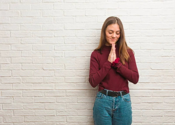Young cool woman over a bricks wall praying very happy and confident