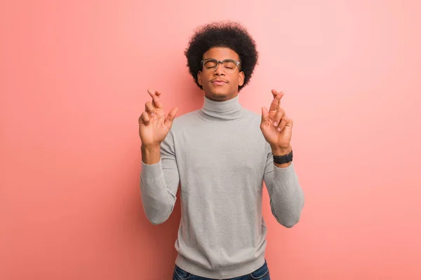 Giovane Uomo Afroamericano Sopra Muro Rosa Incrociando Dita Avere Fortuna — Foto Stock