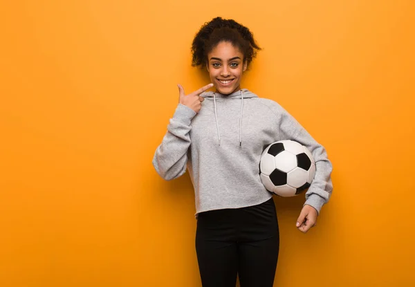 年轻的健身黑人女人笑了 指着嘴 拿着足球 — 图库照片