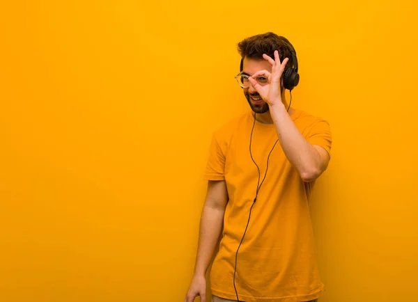 stock image Young man listening to music confident doing ok gesture on eye