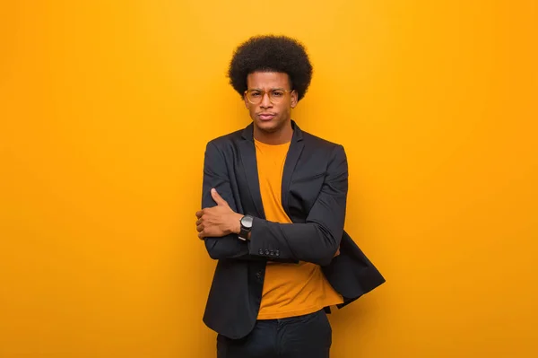 Young business african american man over an orange wall crossing arms relaxed