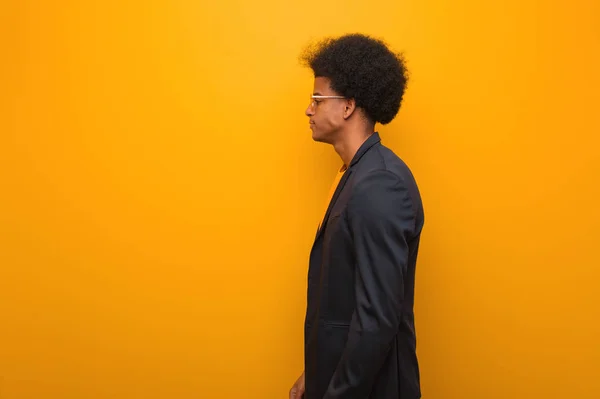 Young business african american man over an orange wall on the side looking to front