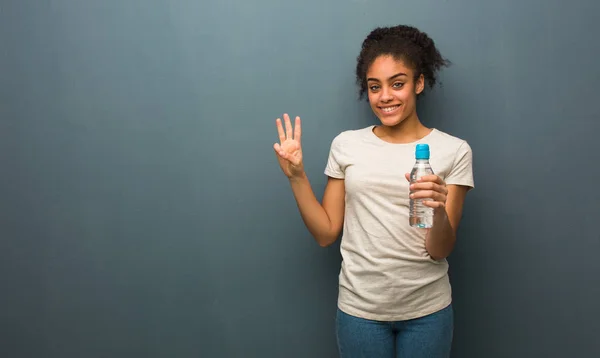 Молодая Черная Женщина Показывает Номер Три Держит Бутылку Водой — стоковое фото