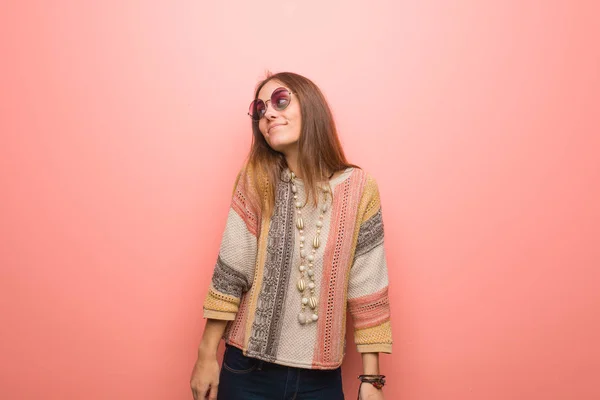 Young hippie woman on pink background dreaming of achieving goals and purposes