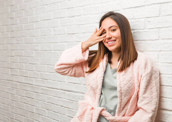 Young woman wearing pajama embarrassed and laughing at the same time