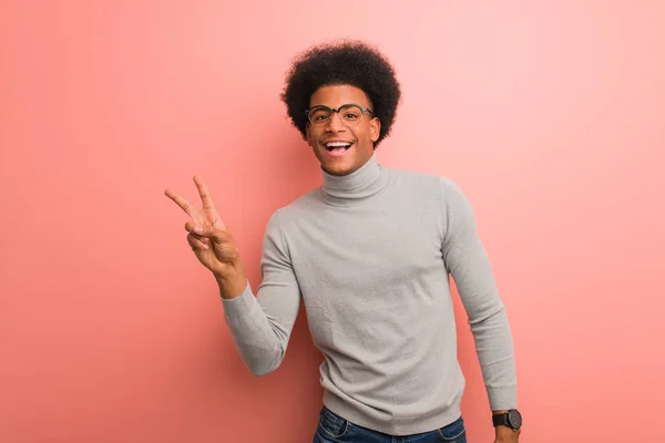年轻的非洲裔美国人在粉红色的墙壁做一个胜利的姿态 — 图库照片