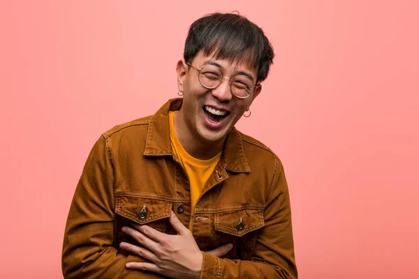 Young chinese man wearing a jacket laughing and having fun