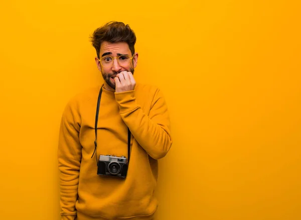 Young photographer man biting nails, nervous and very anxious