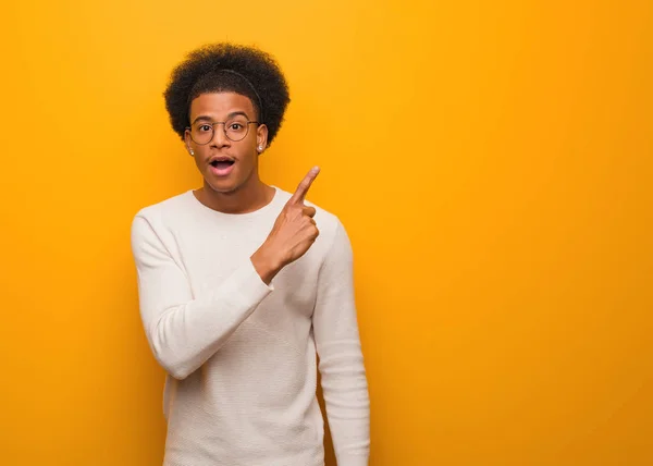 Jovem Afro Americano Sobre Uma Parede Laranja Apontando Para Lado — Fotografia de Stock