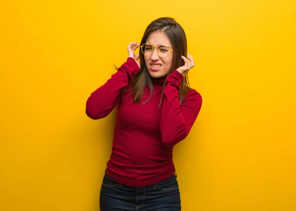 Young intellectual woman covering ears with hands