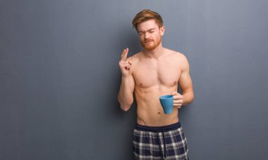 Genç, üstsüz, kızıl saçlı adam şans dilemek için şans diliyor. Elinde bir kahve fincanı var..