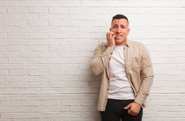 Tırnak yiyen genç latin adam, gergin ve çok endişeli.