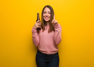 Bir numarayı gösteren bir bira tutan genç ve tatlı bir kadın.