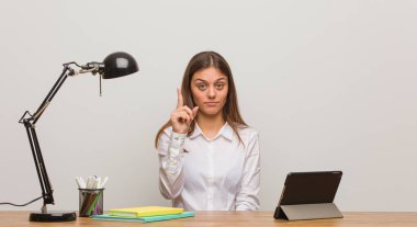 Masasında çalışan genç bayan bir numarayı gösteriyor.