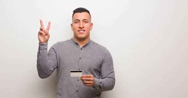 Young Latin Man Holding Credit Card Showing Number Two — Stock Photo, Image