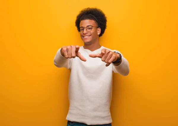 Mladý Africký Američan Přes Oranžovou Zeď Veselý Úsměvem Ukazuje Dopředu — Stock fotografie