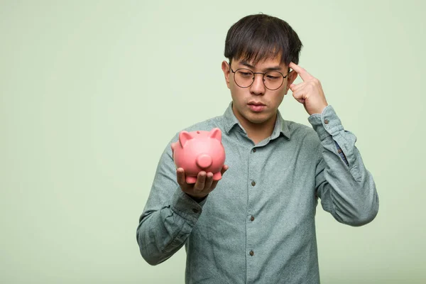 Jovem Asiático Homem Segurando Porquinho Banco Pensando Sobre Uma Ideia — Fotografia de Stock